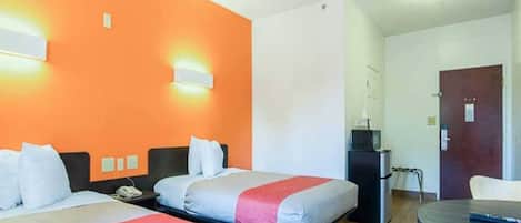 Habitación de hotel con dos camas, un escritorio, un refrigerador y una puerta.