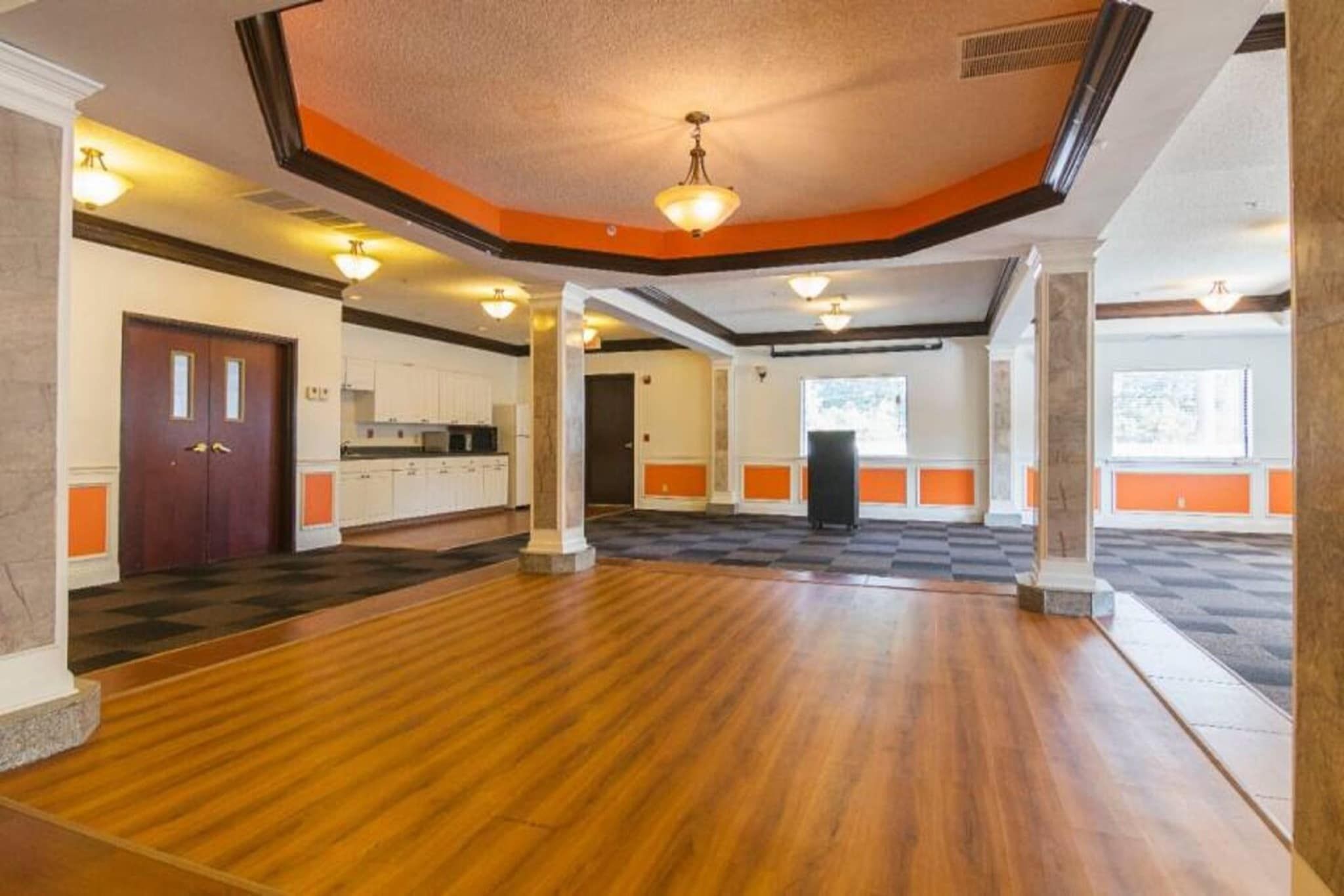 Um quarto espaçoso com piso de madeira, cozinha e uma janela grande.