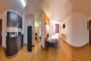Ein kleines Hotelzimmer mit Küchenzeile, einem Bett und einem Badezimmer.