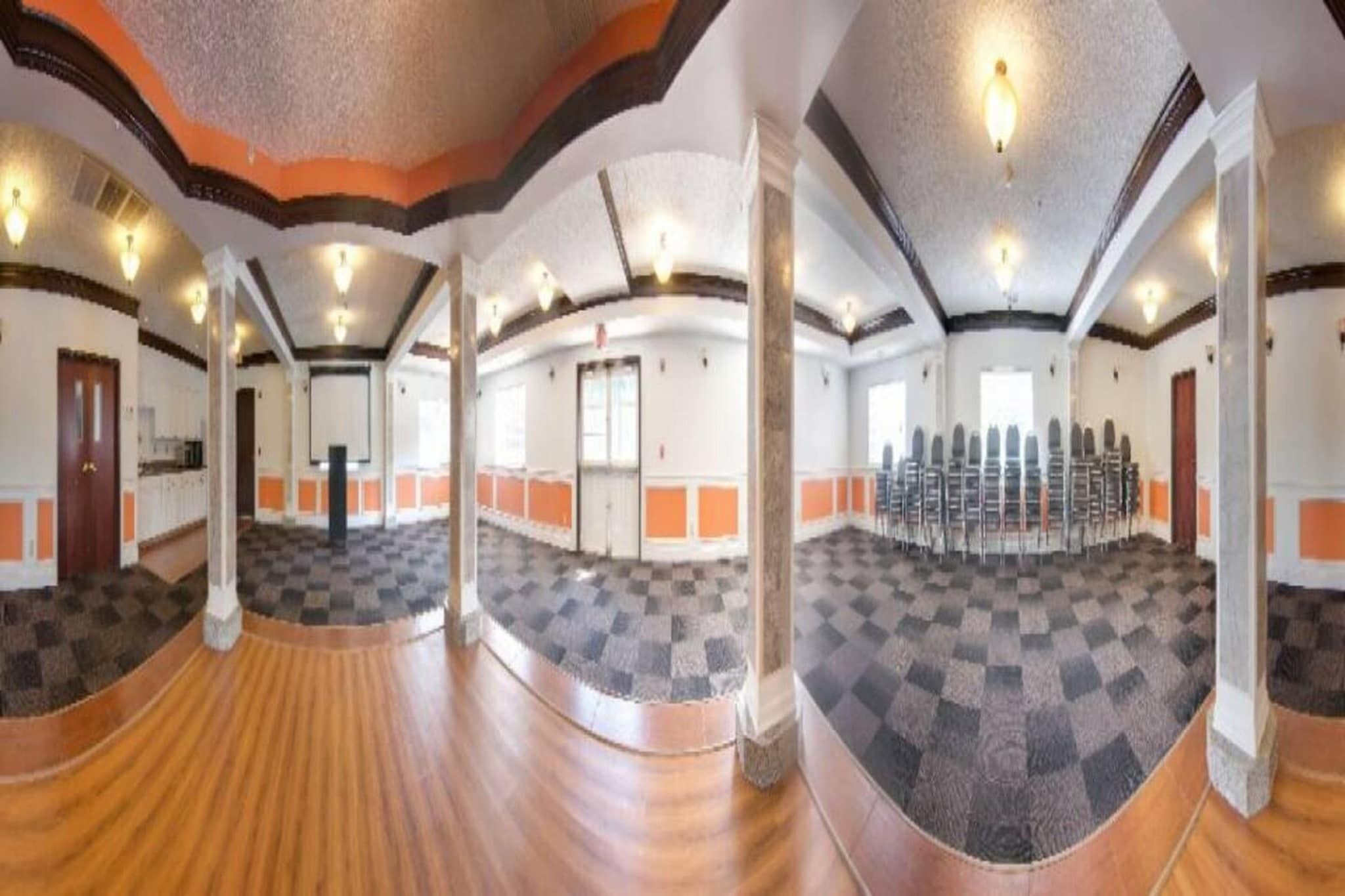 A spacious hall with a checkered floor, wooden flooring, and a seating arrangement.