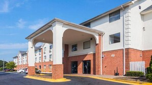 A hotel with a covered entrance, brick facade, and a parking lot. - Comfy Full Beds|Free Wifi &Parking (Jonesboro)