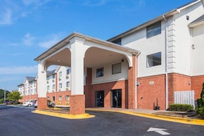 Ein Hotel mit überdachter Einfahrt, Backsteinfassade und Parkplatz.