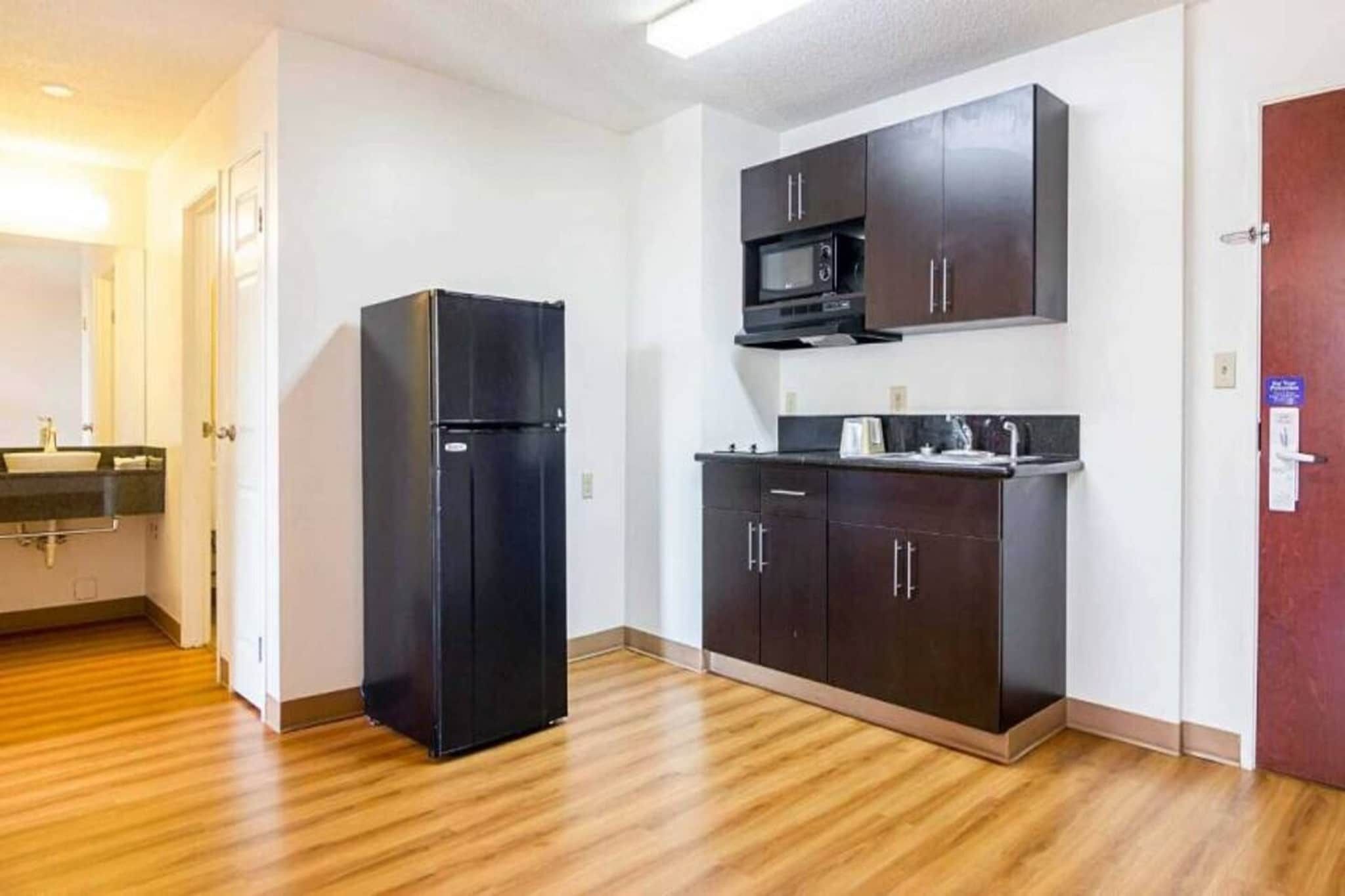 A compact kitchen with a refrigerator, microwave, and dark cabinets.