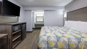 Una camera d'albergo con un letto, una TV, una scrivania e uno specchio.