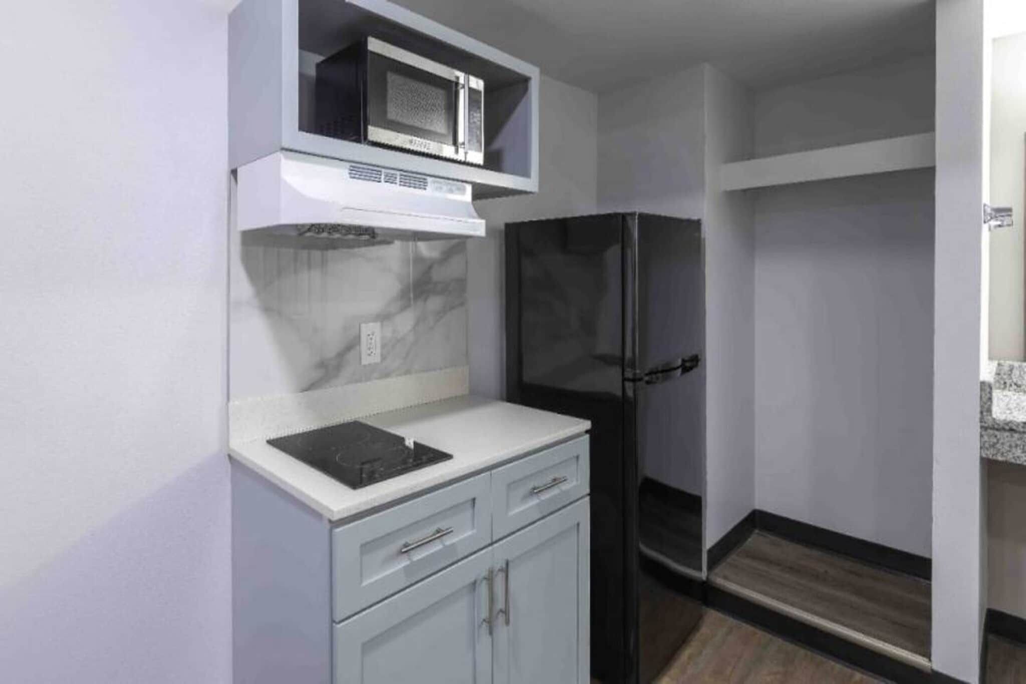 Una cucina compatta con forno a microonde, frigorifero e un piccolo bancone.