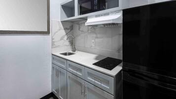 A kitchen with a black refrigerator, a microwave, a sink, and a stove.