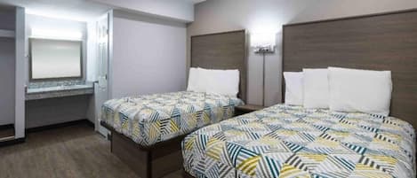 Une chambre d’hôtel avec deux lits, un bureau et un miroir.