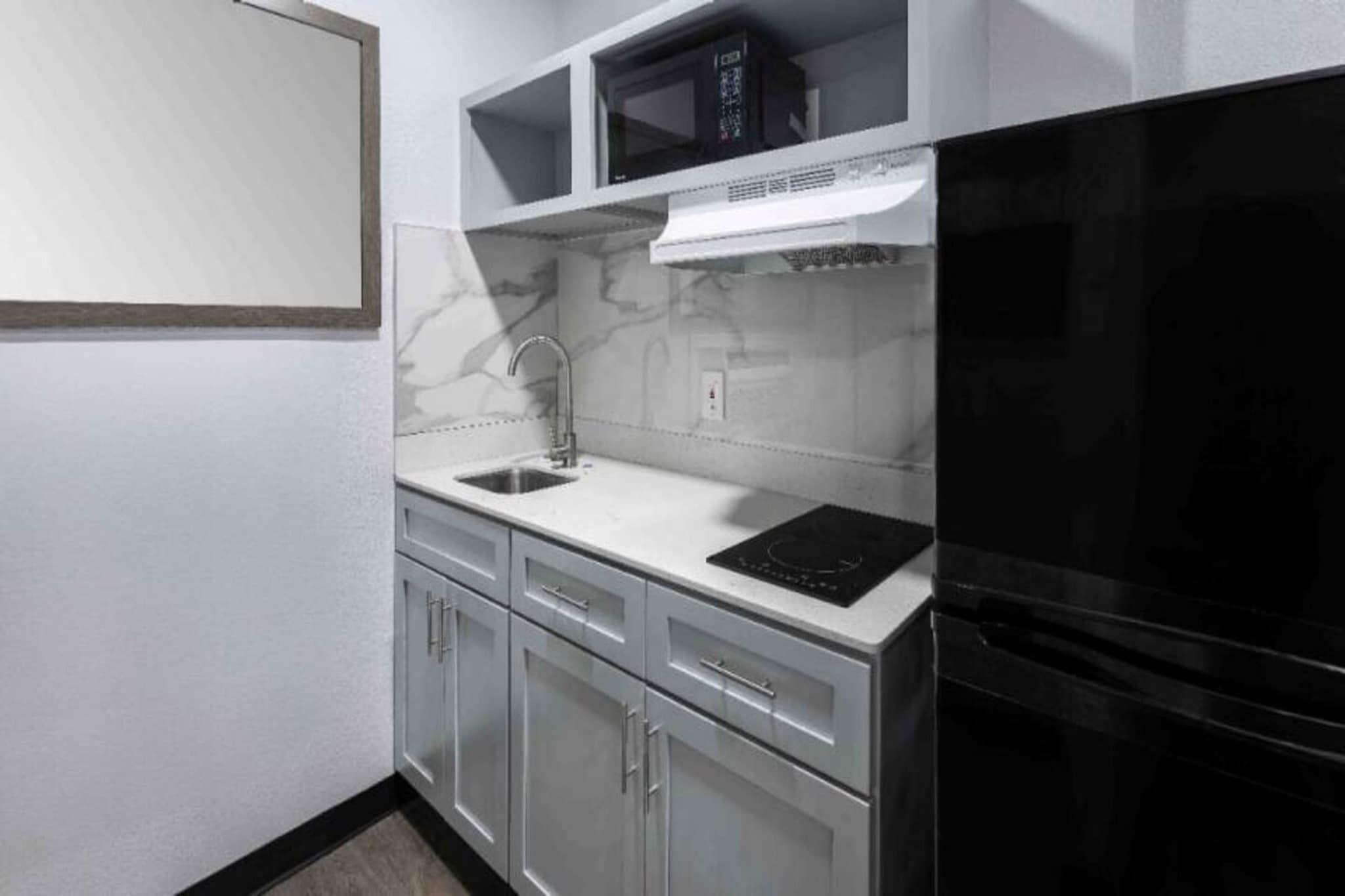 A kitchen with a black refrigerator, a microwave, a sink, and a stove.