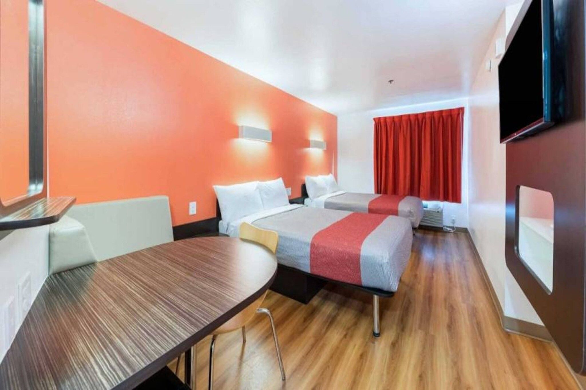 A hotel room with two beds, a wooden table, and a TV.