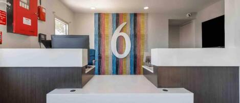 A reception area with a large number '6' on the wall, a red fire extinguisher, and a flat-screen TV.