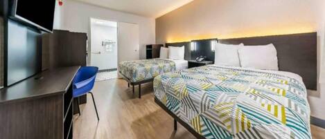 A hotel room with a bed, a desk, a chair, and a television.