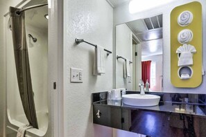Un baño con ducha, lavabo y espejo.