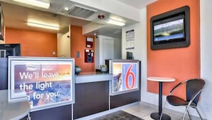 A hotel reception area with a counter, a chair, and a television mounted on the wall. - 2 Full Beds | Micfridge, Smoking (Flaggstaff)