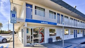 Um motel de dois andares com uma placa de 'Welcome', estacionamento acessível para deficientes e entrada acessível para vans.