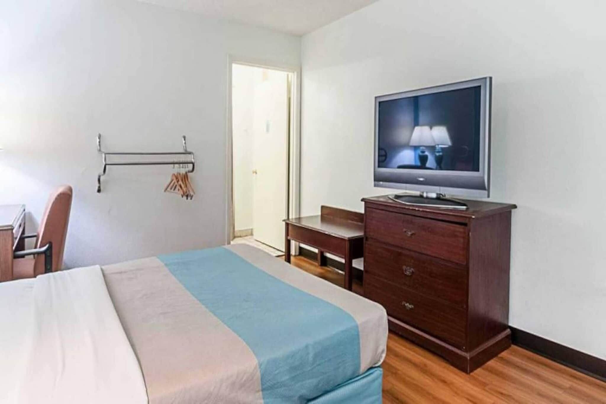 Ein Hotelzimmer mit einem Bett, einem Schreibtisch, einem Sessel, einem Fernseher und einem Kleiderschrank.