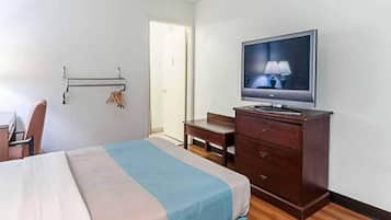 Ein Hotelzimmer mit einem Bett, einem Schreibtisch, einem Sessel, einem Fernseher und einem Kleiderschrank.