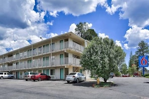 A multi-story motel with a parking lot, several cars parked, and a clear sky with clouds. - 2 Full Beds | Premium, Micfridge (Flagstaff AZ)