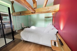 Ein Hotelzimmer mit Bett, Holzbalken, einer roten Wand und einem Holzboden.