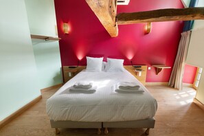 Ein Hotelzimmer mit einem großen Bett, zwei Nachttischen und einem Holzbalken an der Decke.