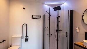Uma casa de banho moderna com cabine de duche em vidro, sanita e lavatório com espelho.