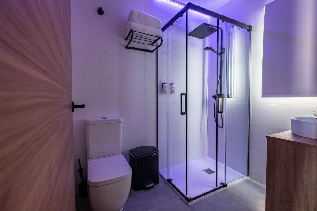 Un baño moderno con ducha de vidrio, inodoro y lavamanos.