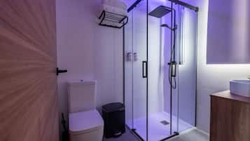 Un baño moderno con ducha de vidrio, inodoro y lavamanos.