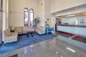 Un vestíbulo de hotel con sofás estampados, un mostrador de recepción y un ventanal grande.