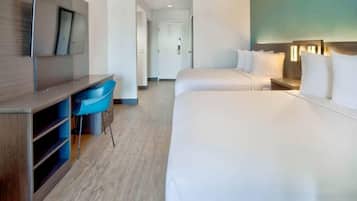 A hotel room with a bed, a desk, a chair, and a television.