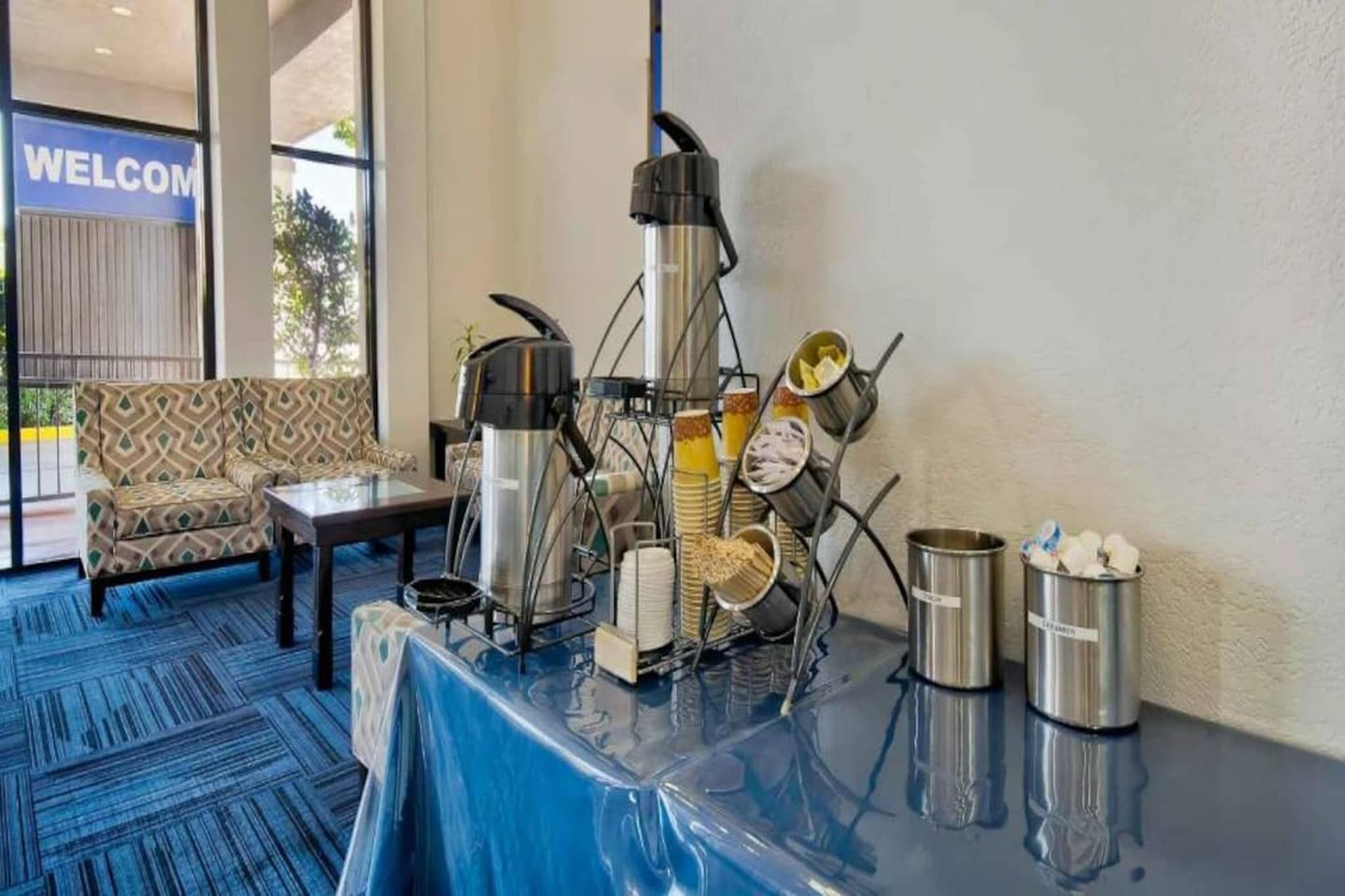 A buffet setup with a coffee machine, stacked plates, and condiment containers.