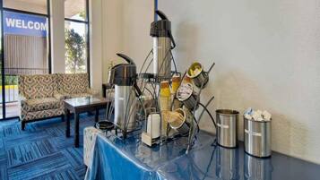 A buffet setup with a coffee machine, stacked plates, and condiment containers.