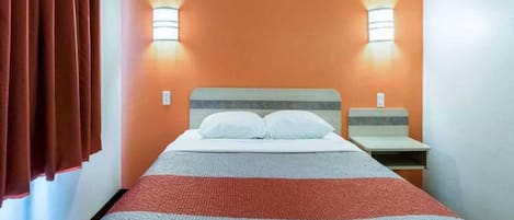 A hotel room with a bed, two bedside tables, and two wall-mounted lamps.