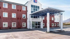 Een hotel met een gevel van rode baksteen, een overdekte ingang en een heldere lucht.
