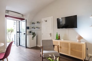 A modern living room with a flat-screen TV, a wooden cabinet, a grey armchair, and a red chair. - The Burgundy Nest by Campo de Fiori (Roma)
