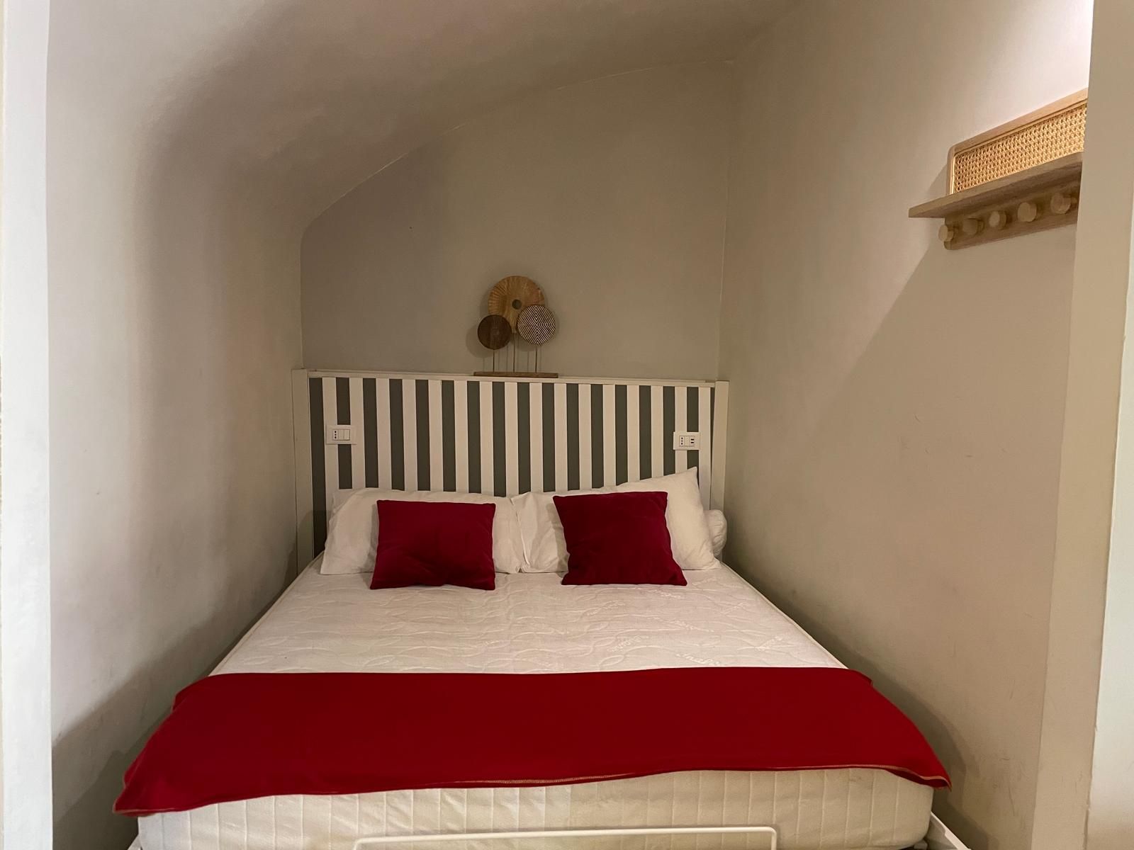Une petite pièce avec un lit, des murs blancs et une tête de lit à rayures.