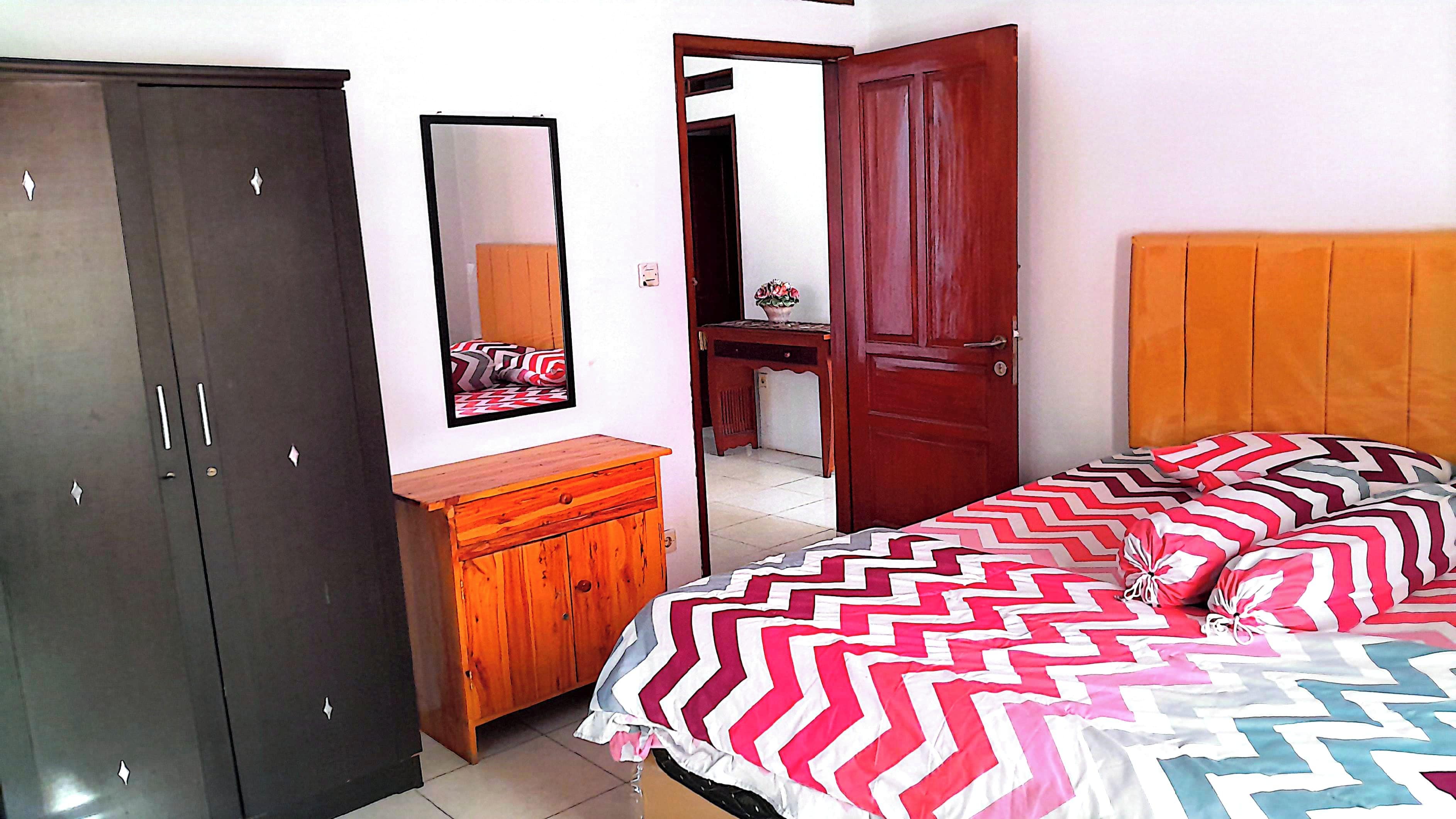 Une chambre à coucher comprenant un lit, une armoire, une commode et un miroir.
