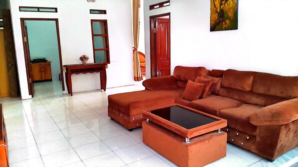 A living room with a brown sofa, a matching ottoman, and a coffee table. - Villa Dinar Strawberry (Bandung Barat)