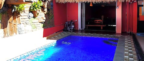 A swimming pool with a tiled edge and a stone wall on one side.