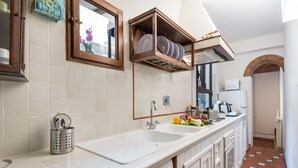 Una cucina con un lavello doppio, un fornello e un forno a microonde. Sono presenti armadietti e una finestra sopra il lavello.