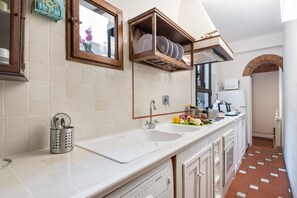A kitchen with a double sink, a stove, and a microwave. There are cabinets and a window above the sink. - Giulia Suite: Florentine Home in the Heart of Florence (Firenze)