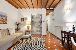 A cozy living room with a sofa, a coffee table, and a patterned rug. - Giulia Suite: Florentine Home in the Heart of Florence (Firenze)
