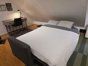 A bedroom with a bed, a desk, a chair, and a rug. - The Loft in Golden | Downtown · King Bed (Golden)