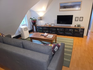A living room with a sofa, a coffee table, a TV, and storage units. - The Loft in Golden | Downtown · King Bed (Golden)