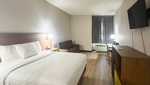 Habitació d'hotel amb un llit gran, escriptori, cadira i televisió penjada a la paret.