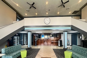 En lobby med receptionsdisk, siddeområde og et ur på væggen.