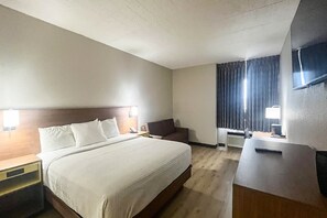 A hotel room with a bed, bedside tables, a desk, a chair, a television, and a window with curtains. - 1 Queen Bed | Nsmk, Micfridge, Sofa-Bed (Fremont (OH))