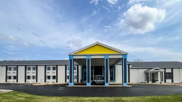 Um edifício com teto amarelo e colunas azuis, um estacionamento e um céu limpo.