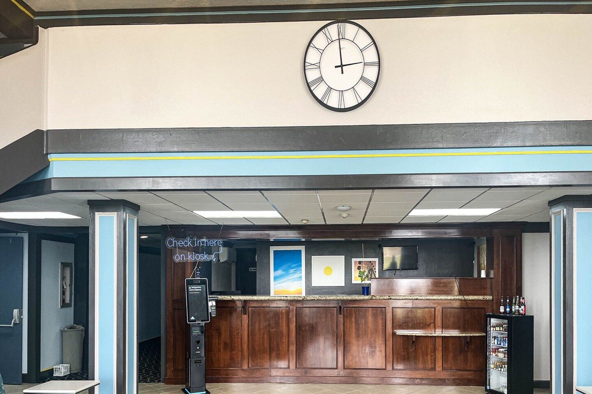 Uma área de recepção com relógio, balcão de check-in e bar.