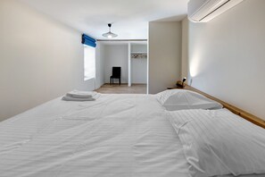 A bedroom with a bed, a chair, and a wardrobe. - Holiday Home 'La Colonie - Grange Arthuis' with Private Terrace, Wi-Fi and Air Conditioning (Lavau)