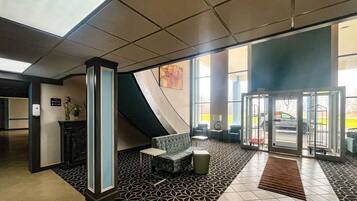 A lobby with a reception desk, seating area, and a glass door entrance.