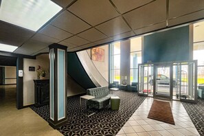 Un hall con mostrador de recepción, zona de estar y entrada por puerta de cristal.